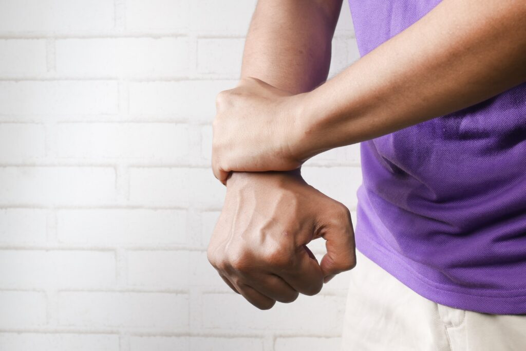 Person wearing a purple shirt holding their wrist